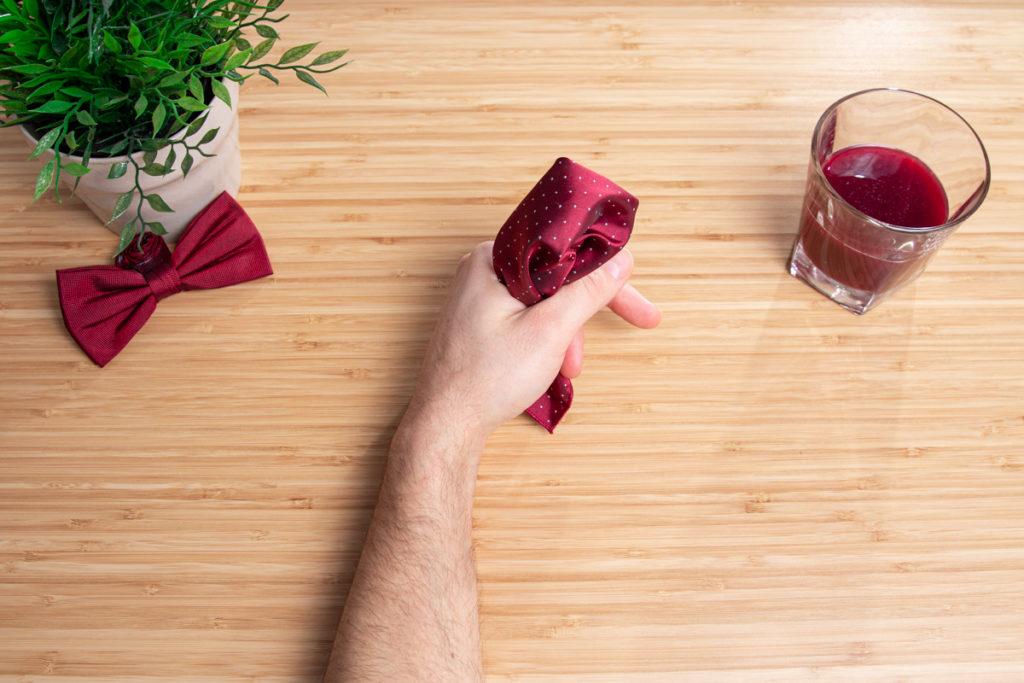folding a red pocket square with two hand on the wooden table 